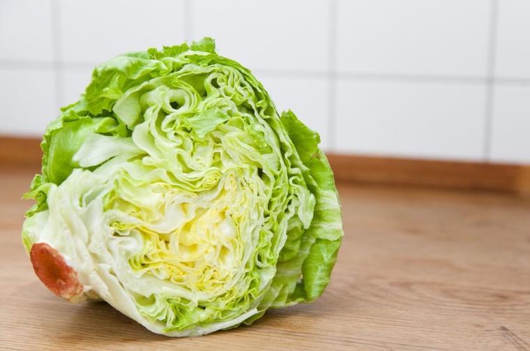 A head of lettuce on a wooden surface.