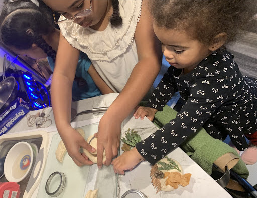 Two children playing at a table with clay and art supplies.