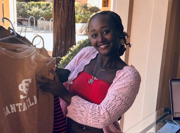 Student worker holding a SCU sweatshirt at Bucky's Closet checkout 