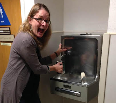 A person filling a water bottle at a filling station.
