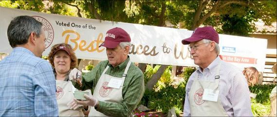 Four people talking outside near a sign with 