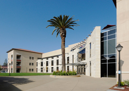 A modern building complex with a palm tree and clear blue sky. image link to story