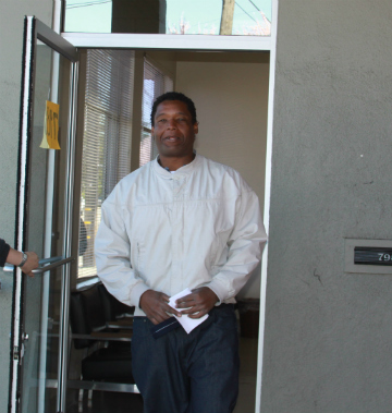 Person holding a document, standing in a doorway.