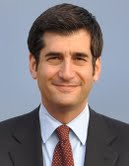 A person smiling in a suit and tie.