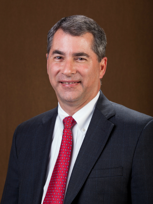 A person in a dark suit with a red tie. image link to story