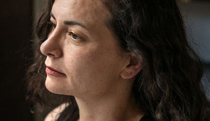 A woman gazing to the side in dim lighting. image link to story