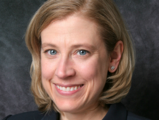 A woman smiling against a dark background. image link to story