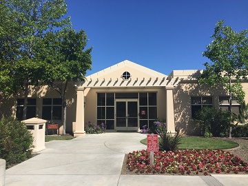 An entrance of a building with trees and a walkway.