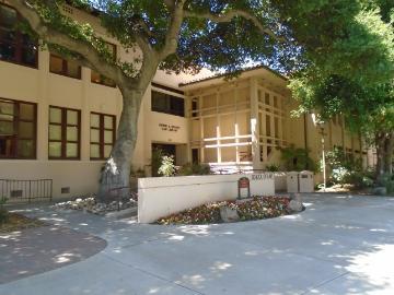 Alt text: Entrance of Heafy Law Library with tree shade and outdoor seating area.