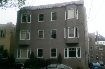 A three-story brick apartment building with multiple windows.
