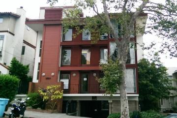 A red-brick building with trees and greenery in front.