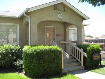 A small house with a front porch and bushes.