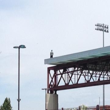 Person standing on a roof with steel beams and lighting fixtures.