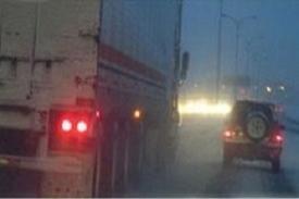 Cars and truck driving on a wet road at night with blurred lights.