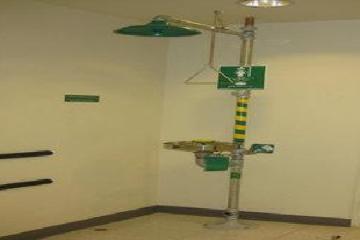 Alt text: Industrial eye wash and safety shower station in a plain room.