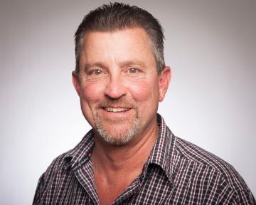 A man wearing a patterned shirt smiling at the camera.