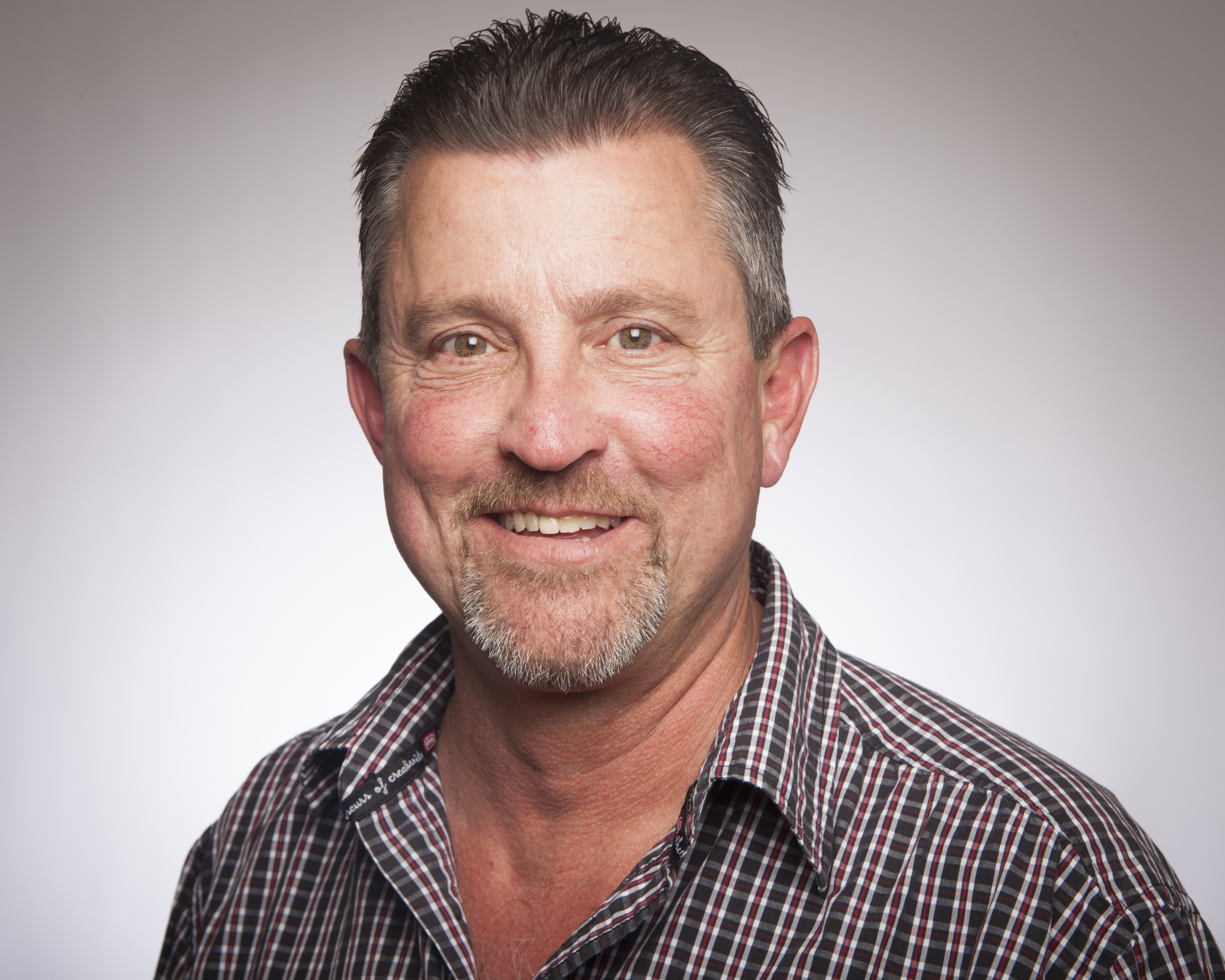 A man wearing a patterned shirt smiling at the camera.