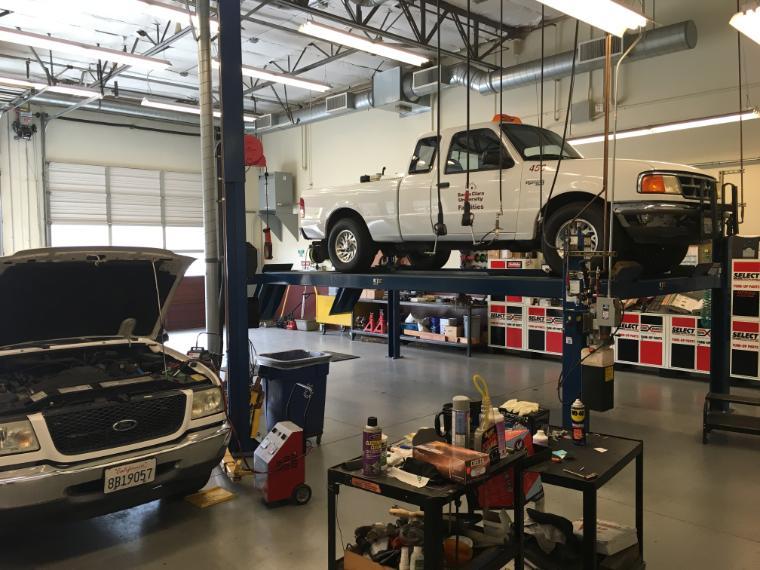 Auto repair shop with cars on lifts and various tools and equipment.