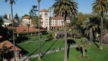 A manicured garden with palm trees and a historic mission building.