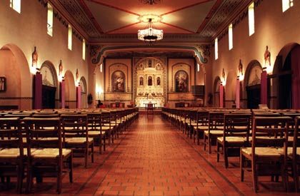 Interior of a church with wooden pews and a lit altar. 