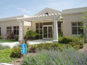 A single-story building surrounded by greenery and plants.