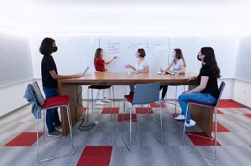 Five students inside an office working on a project 
