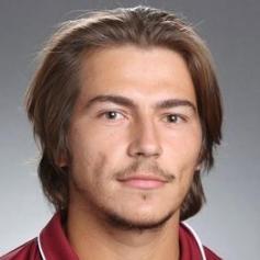 A person wearing a collared shirt against a gray background.