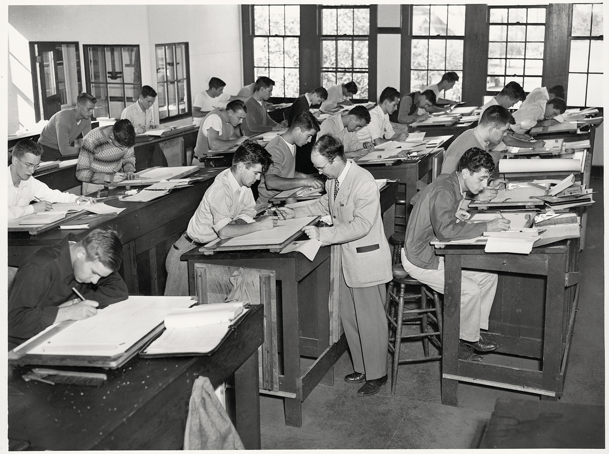 Black and white photo of a professor and students working at drafting tables.