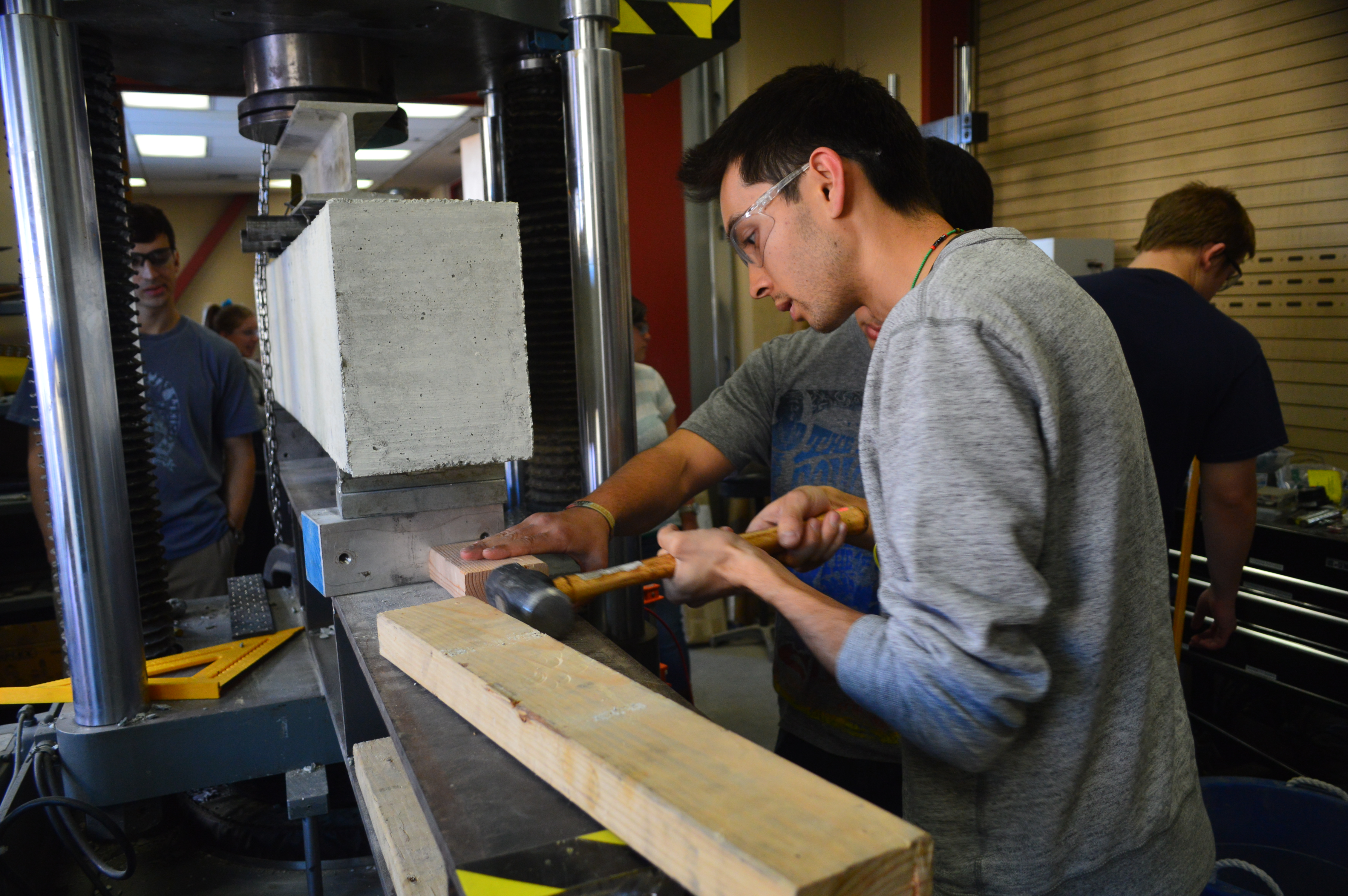 A student prepares a concrete block for testing in a civil engineering laboratory