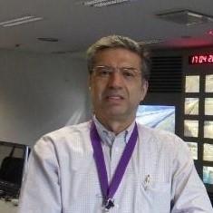 A man with a purple lanyard indoors near computer screens.