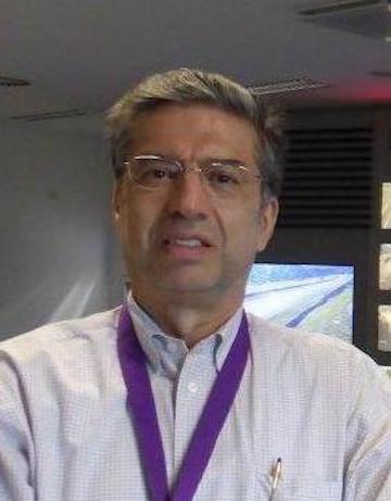 A person wearing a white shirt with a purple lanyard.