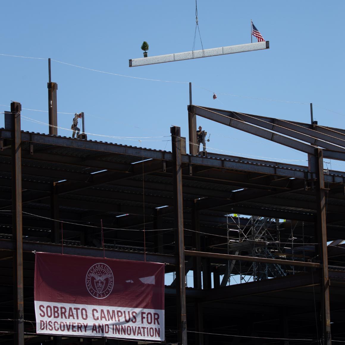 A steel beam is lifted to the top of the Sobrato Campus for Discovery and Innovation building in a topping off ceremony