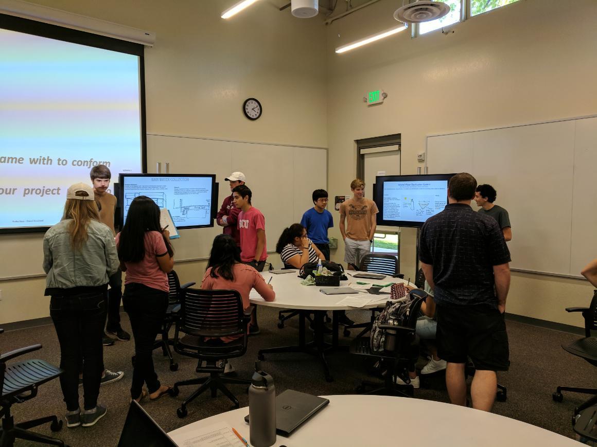 Students presenting posters in classroom during 'Poster Presentation (ENGR 1L)' session.
