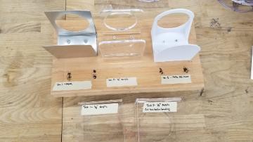 Prototypes for spray bottle holders out of metal, acrylic, and 3D printed.
