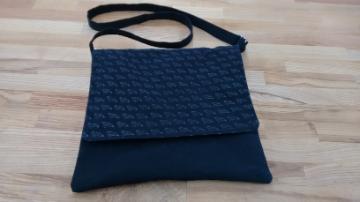 A handmade blue fabric purse with a strap.