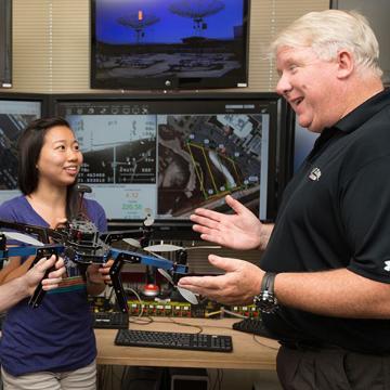 Two people discussing a drone in a tech lab.