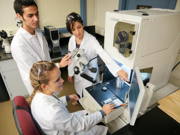 Graduate students and Professor working on equipment and computer in Mechanical Engineering Lab.