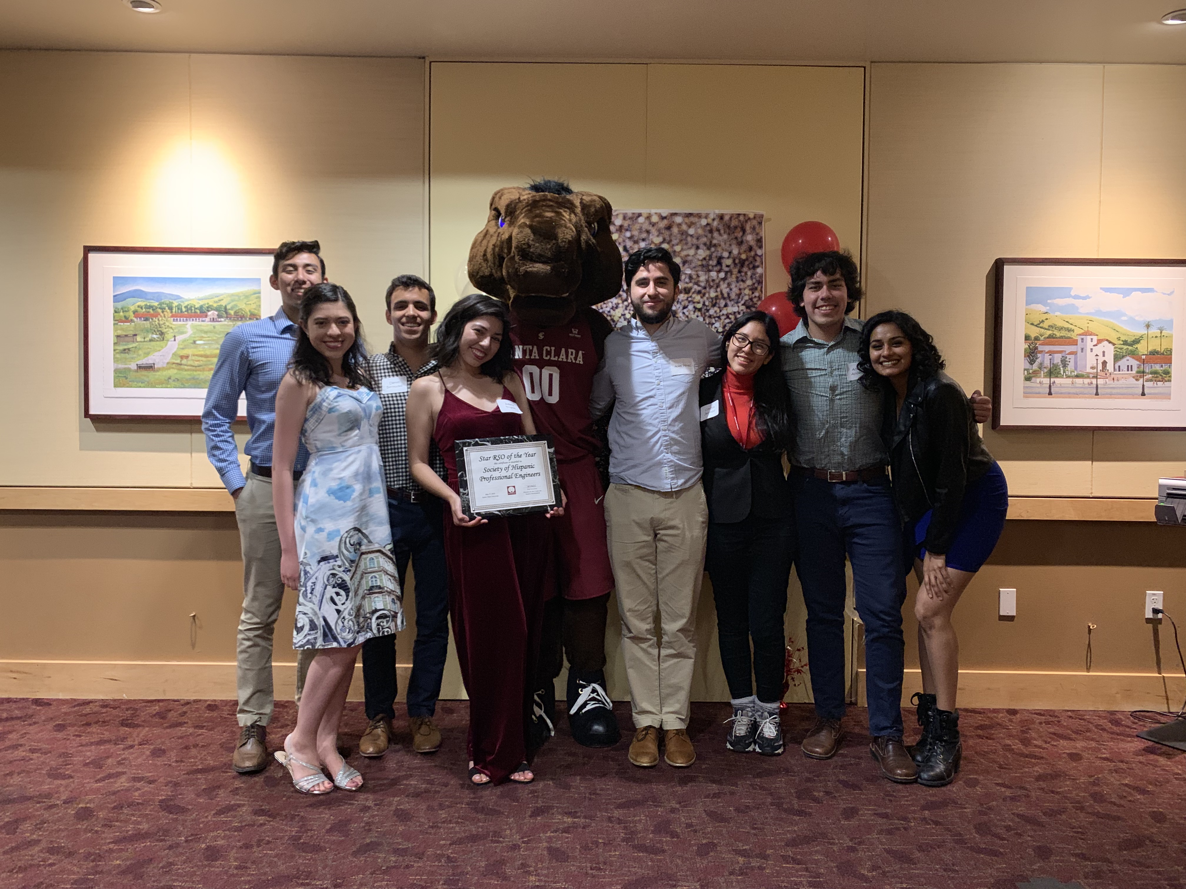 A group of people posing with a mascot, holding a certificate.