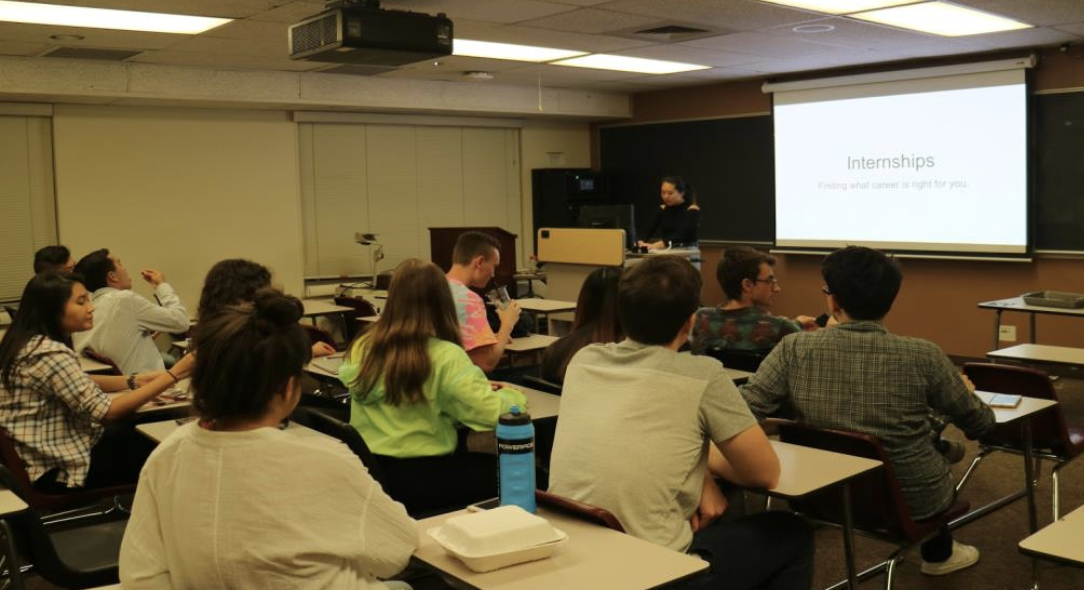 Students in classroom attending a 'Theta Tau Resume' presentation on a screen.
