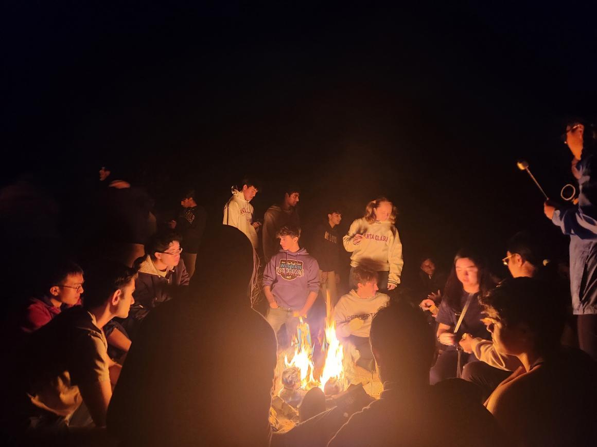 Student sitting around a bonfire.