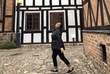 A person in front of a timber-framed building in Lund, Sweden. image link to article