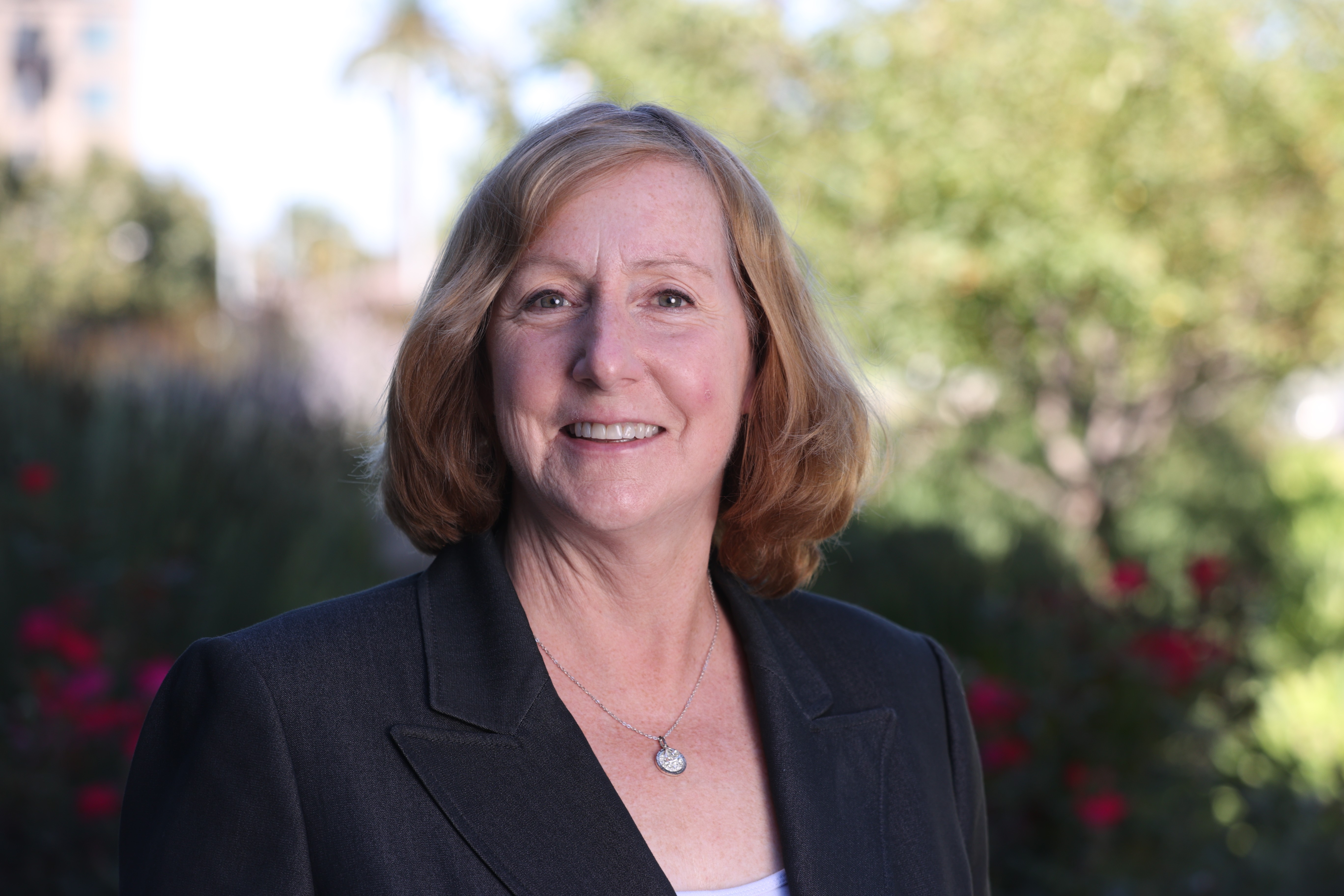 headshot of Joan Wrabetz woman with strawberry blond hair and white skin wearing a navy blazer and a necklace