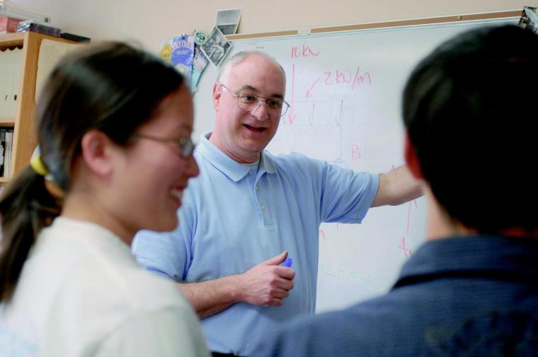 Professor Steven Chiesa in his office helping two students learn a civil engineering concept